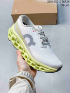 Angled side view of the white and lime On Cloudmonster 3 shoe showing the large side logo, lace closure and segmented midsole.