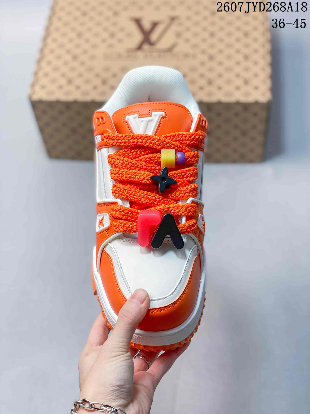 Top view showing the orange laces, decorative lace accessories and white-and-orange toe area.