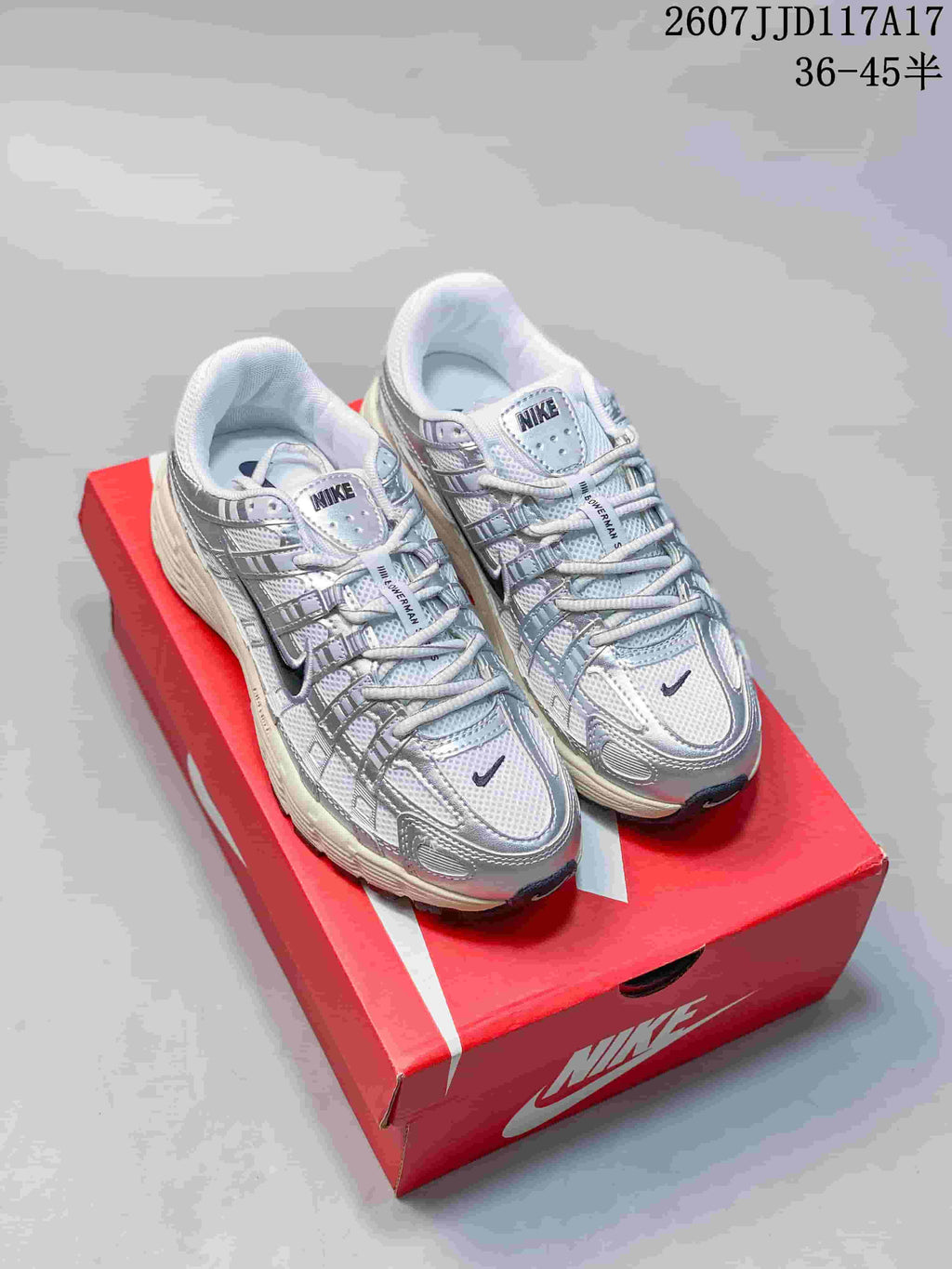 Pair of white and silver Nike P-6000 sneakers displayed on a red shoebox.