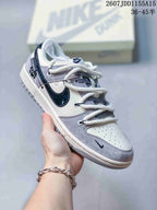 Close-up of a white, gray and navy low-top sneaker with patterned tongue details and contrast side branding.