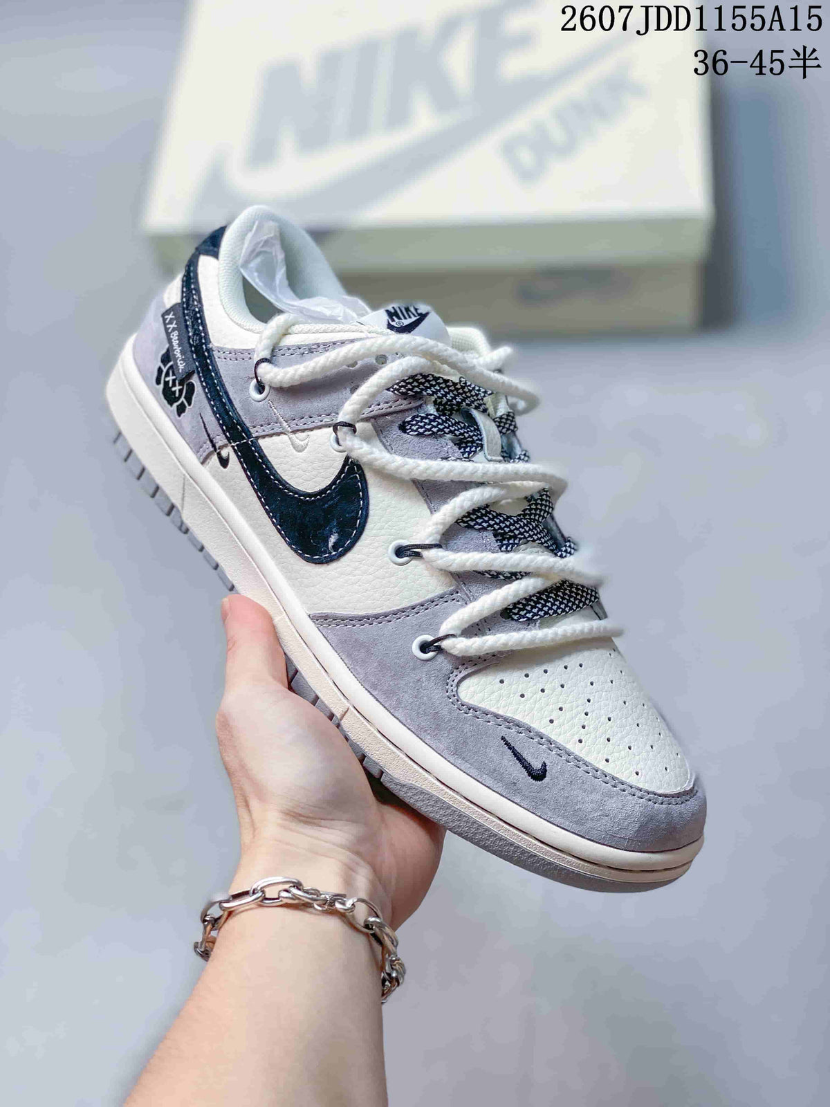 Close-up of a white, gray and navy low-top sneaker with patterned tongue details and contrast side branding.