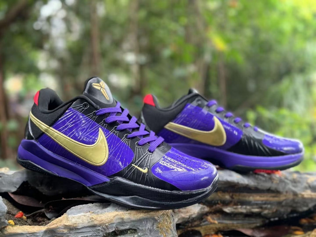 Pair of Nike Kobe 5 basketball shoes in purple, black and gold, shown at an angle.