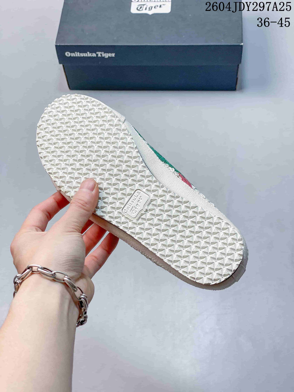 Bottom view of the cream sneaker showing the repeating textured rubber outsole pattern and Onitsuka Tiger mark.