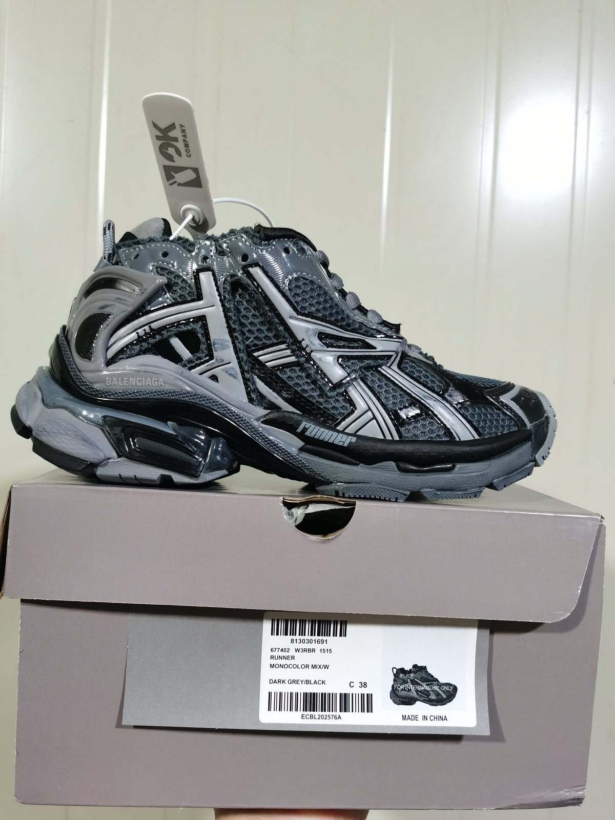 Balenciaga Runner sneaker in dark grey and black displayed on its box; the box label shows RUNNER MONOCOLOR MIX/W, color DARK GREY/BLACK, size C 38, and style code 677402 W3RBR 1515.