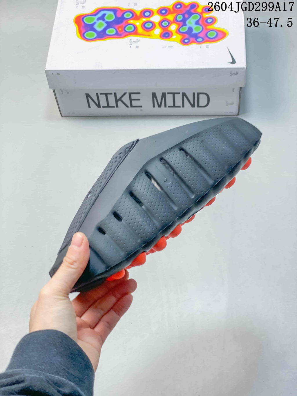 Side view of the Nike Mind slide highlighting the perforated upper, sculpted sidewall, and orange nodes visible under the sole.