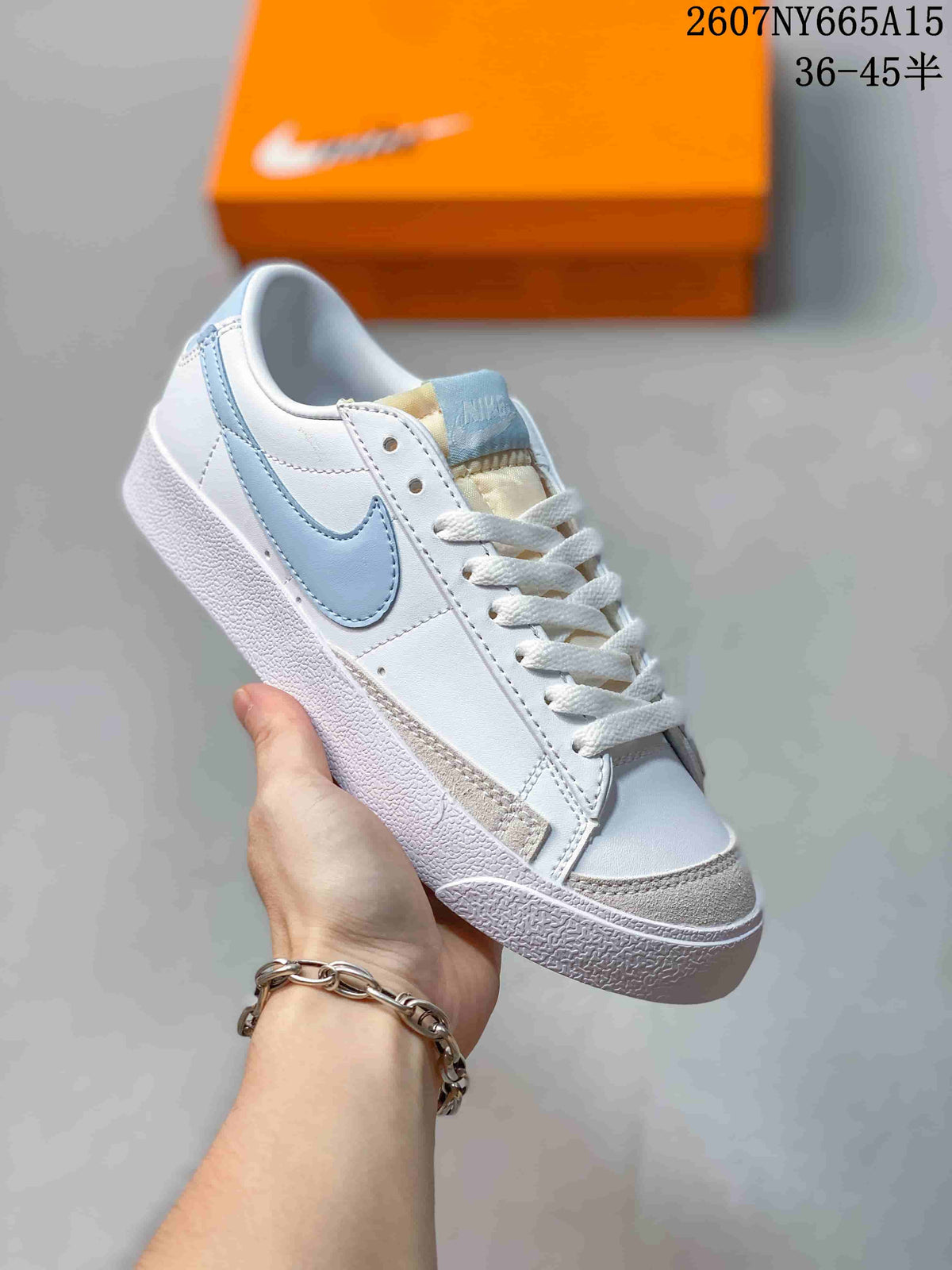 Angled view of a white Nike Blazer Low Premium sneaker with a light blue Swoosh, white laces and a textured sole.