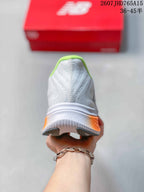 Rear view of the white running shoe showing the lime-green collar and orange heel accent.