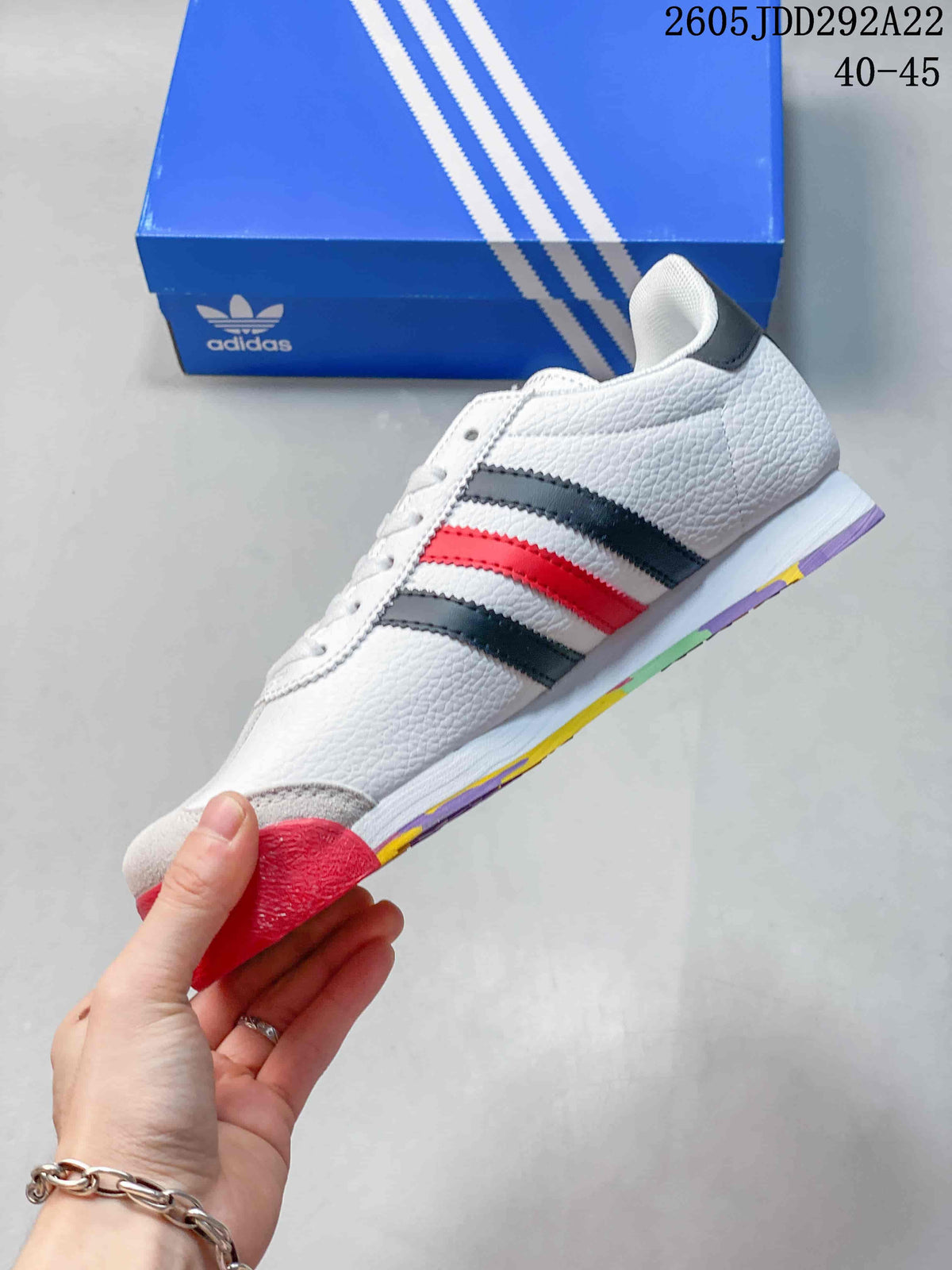 Side profile of the white adidas Samoa sneaker with black and red stripes and a multicolor outsole.