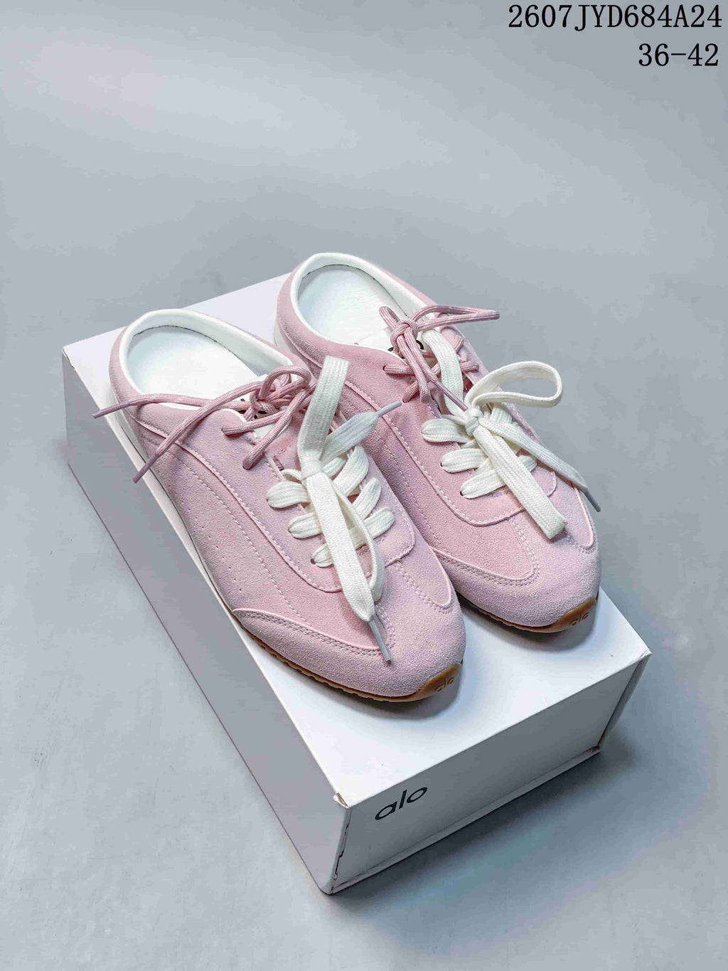 Pair of pink Alo Yoga low-top sneakers with contrasting laces displayed on a white shoebox.