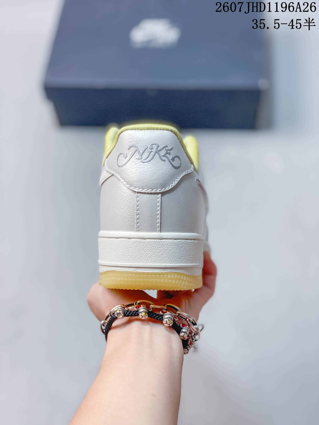 Rear view of the sneaker showing the padded heel, white upper, yellow outsole, and embroidered heel detail.