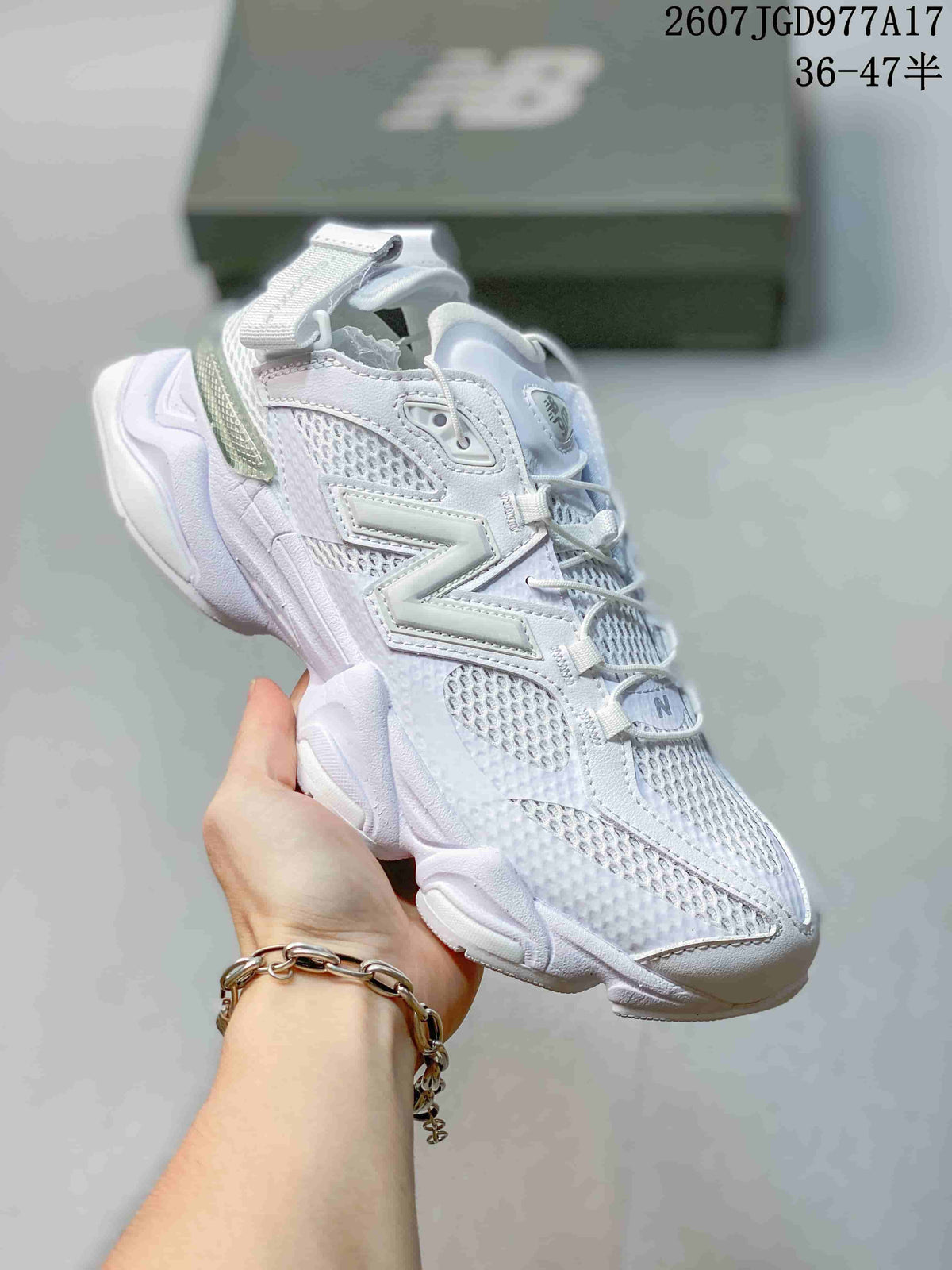 Angled side view of the white New Balance 9060 sneaker with mesh panels, layered side branding, and adjustable heel strap.