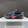 Black Nike low-top sneaker with blue laces, blue-and-pink patterned side accents, and a pink midsole detail.