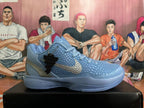 Side view of a blue-gray Nike Kobe basketball shoe showing textured upper and metallic-look Swoosh