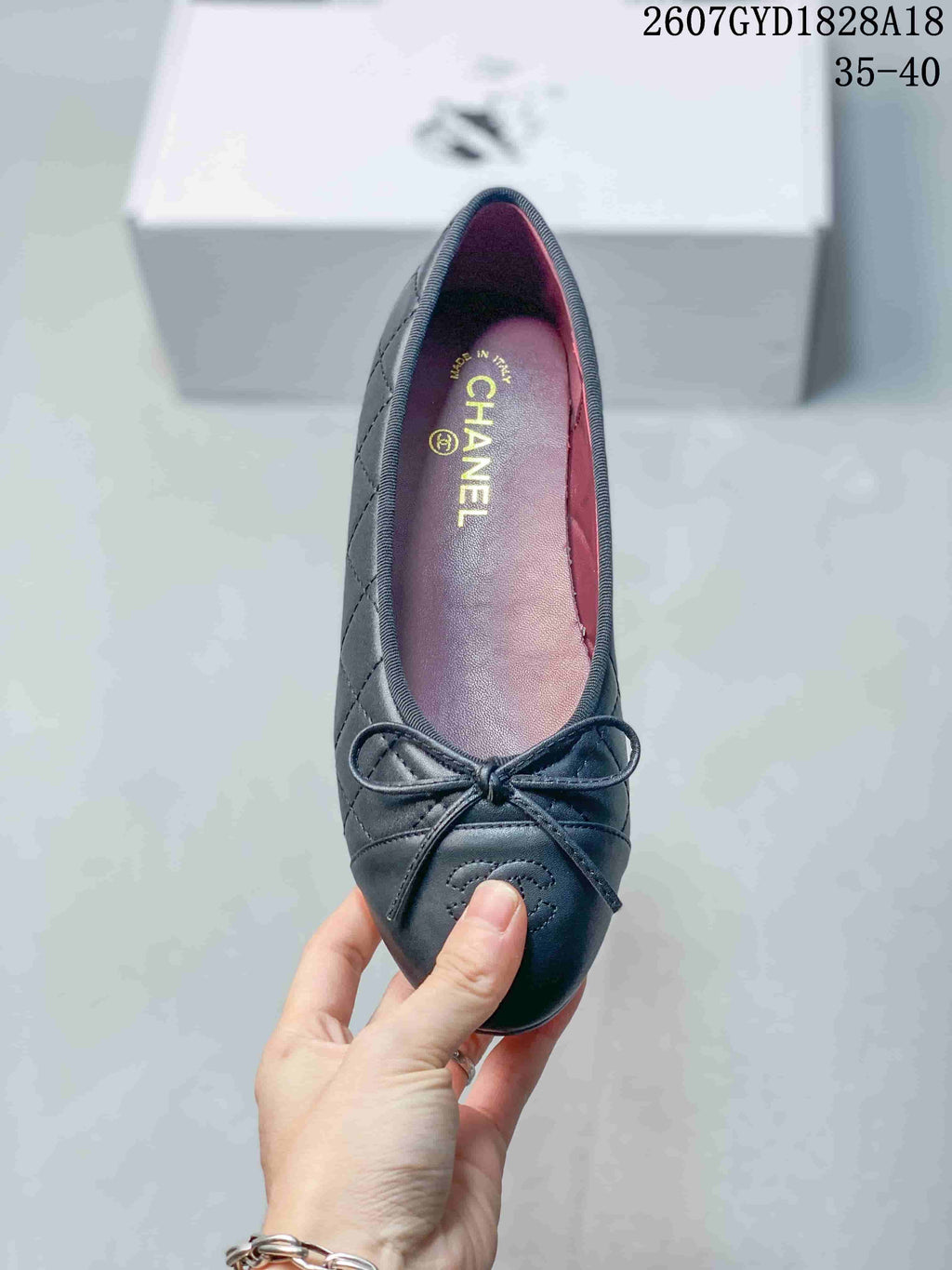 Top view of a black ballet flat with a bow, rounded toe and pink-toned insole.