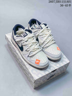 Pair of white low-top sneakers with dark swooshes, patterned laces, and orange toe accents.