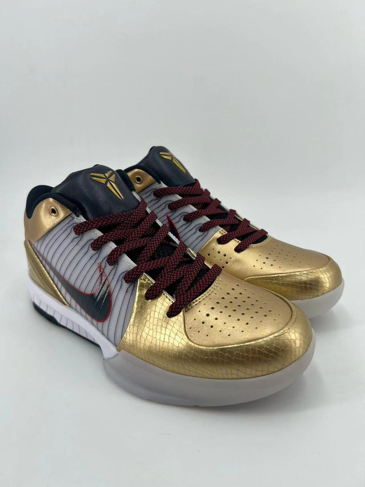 Three-quarter view of the pair highlighting the gold toe overlays and striped side panels.