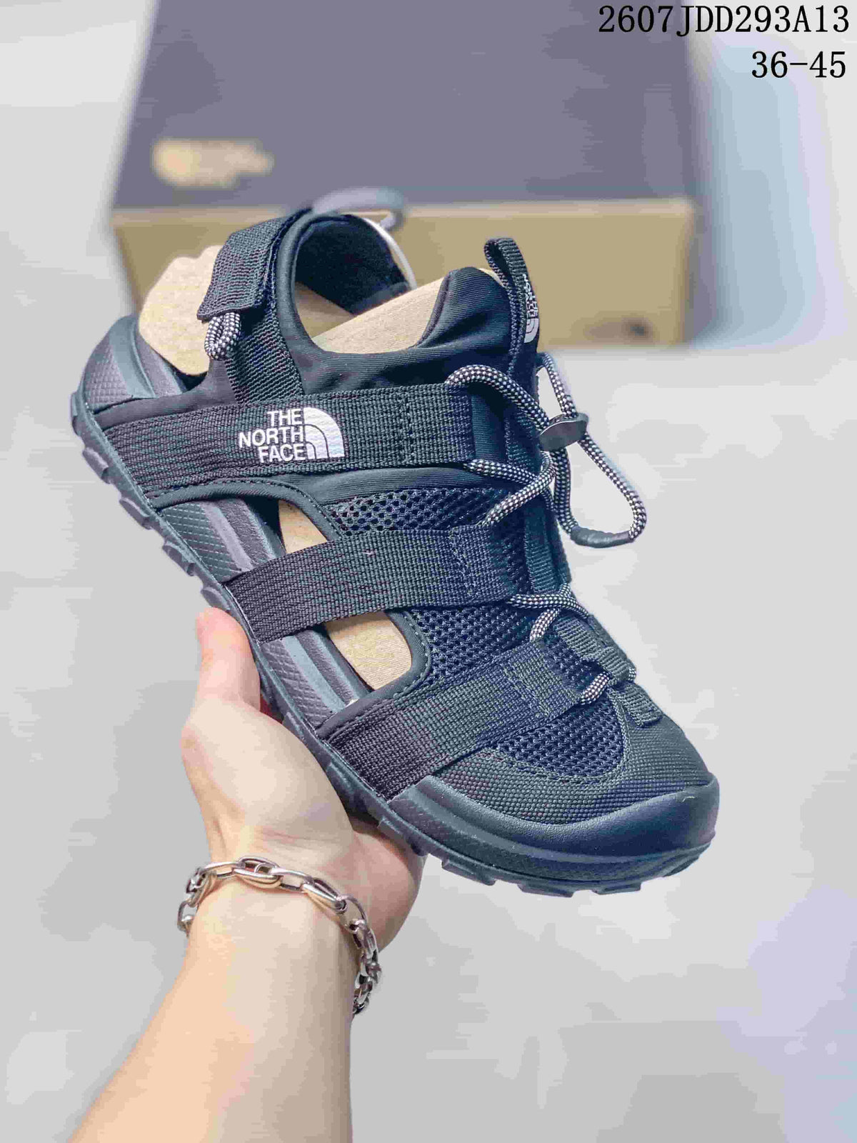 Three-quarter view of a black The North Face sandal showing the adjustable straps, mesh panels, and open side sections.