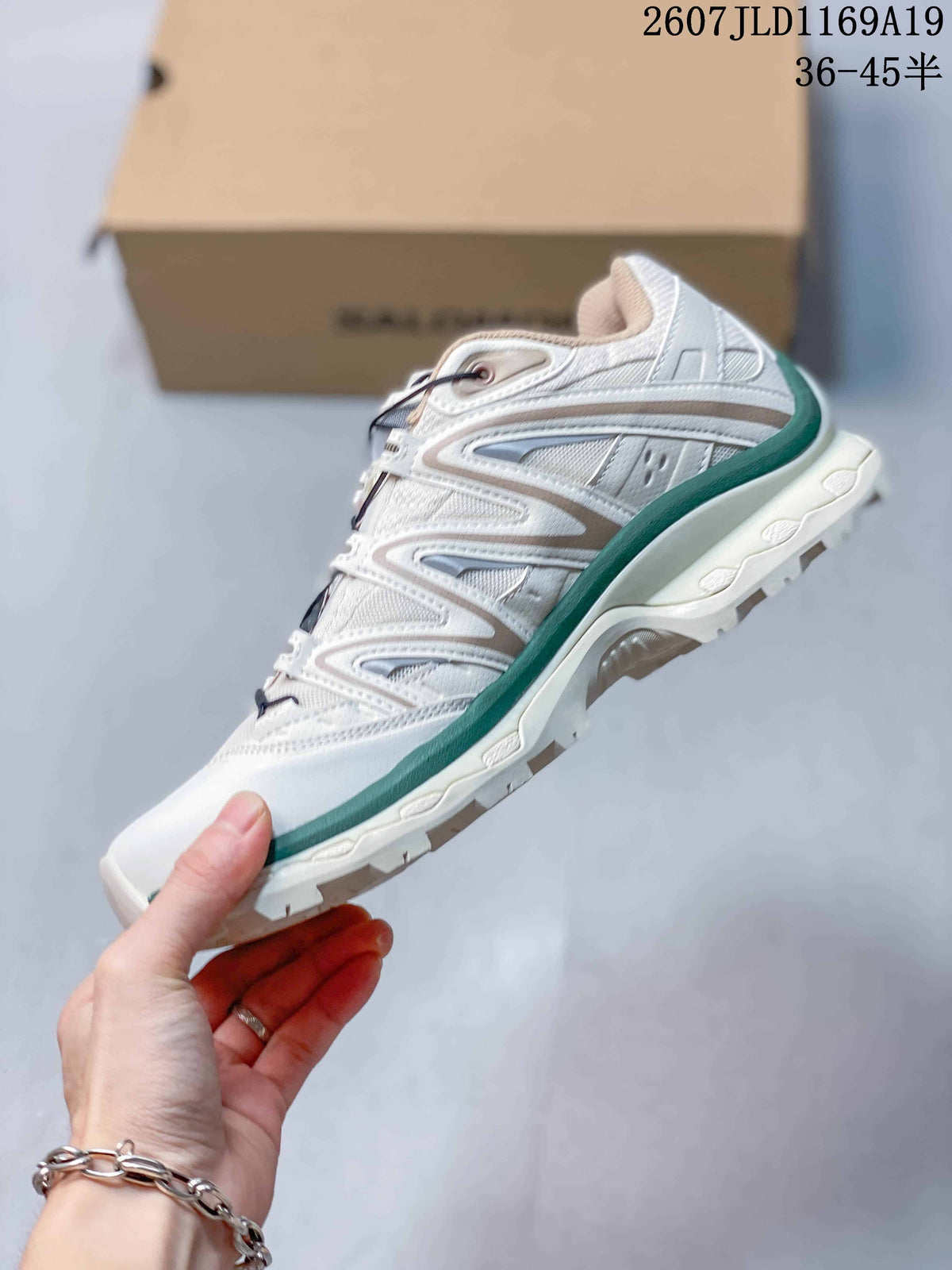 Side view of a white Salomon XT-Quest sneaker with layered gray panels, green trim and a textured outsole.