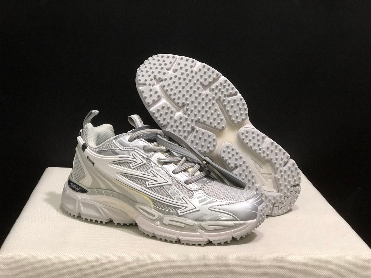 Three-quarter view with one sneaker lifted to display the textured outsole tread and the upper side graphics.