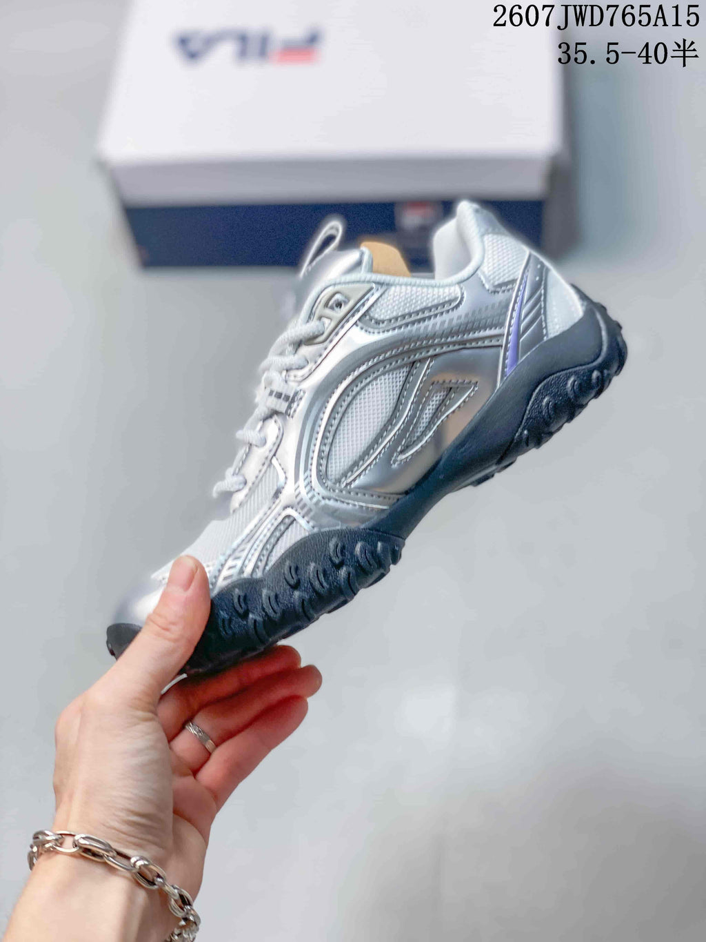 Side profile showing the layered silver and white panels, lace-up front and textured black sole.