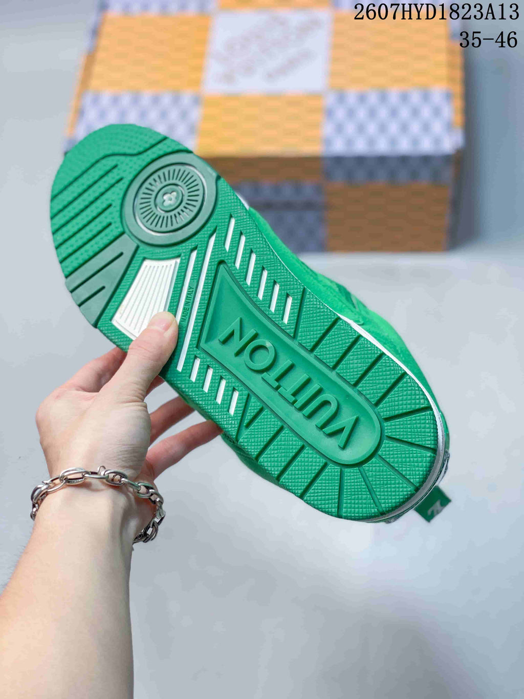 Underside of a green sneaker showing the patterned rubber outsole and raised Louis Vuitton branding.