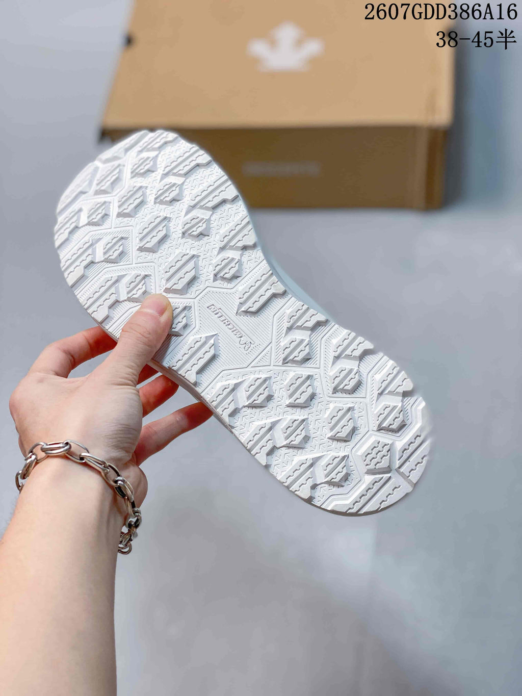 White sneaker outsole shown from below, featuring a geometric patterned tread and raised traction elements.