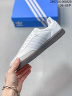 Side profile of the white sneaker showing three stripes, gray toe detailing, and a gum-colored outsole.