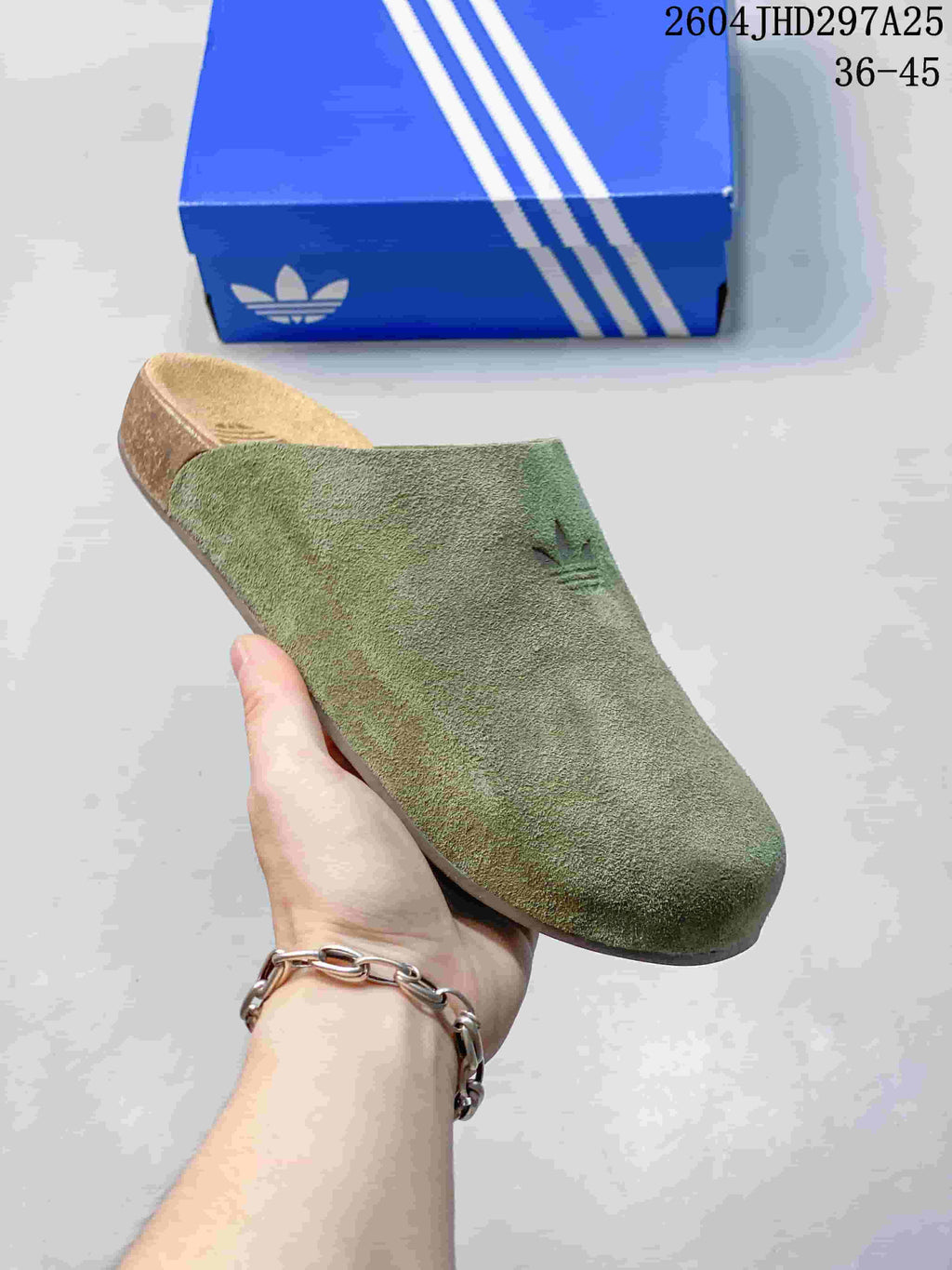 Close-up side view of a green closed-toe Adimule slide showing the textured upper, molded footbed, and outsole.