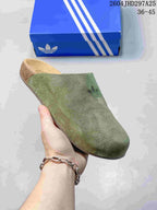 Close-up side view of a green closed-toe Adimule slide showing the textured upper, molded footbed, and outsole.