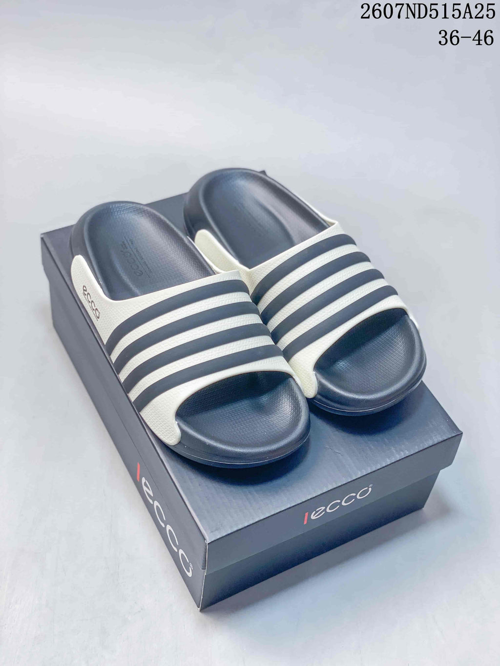 Pair of navy and white ECCO slide sandals displayed on a branded box; style code 2607ND515A25 and size range 36–46 are visible.