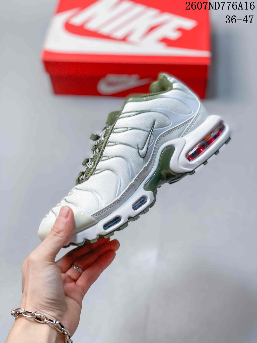 Side view of the white and green sneaker showing layered panels, side swoosh branding, and visible midsole air units.