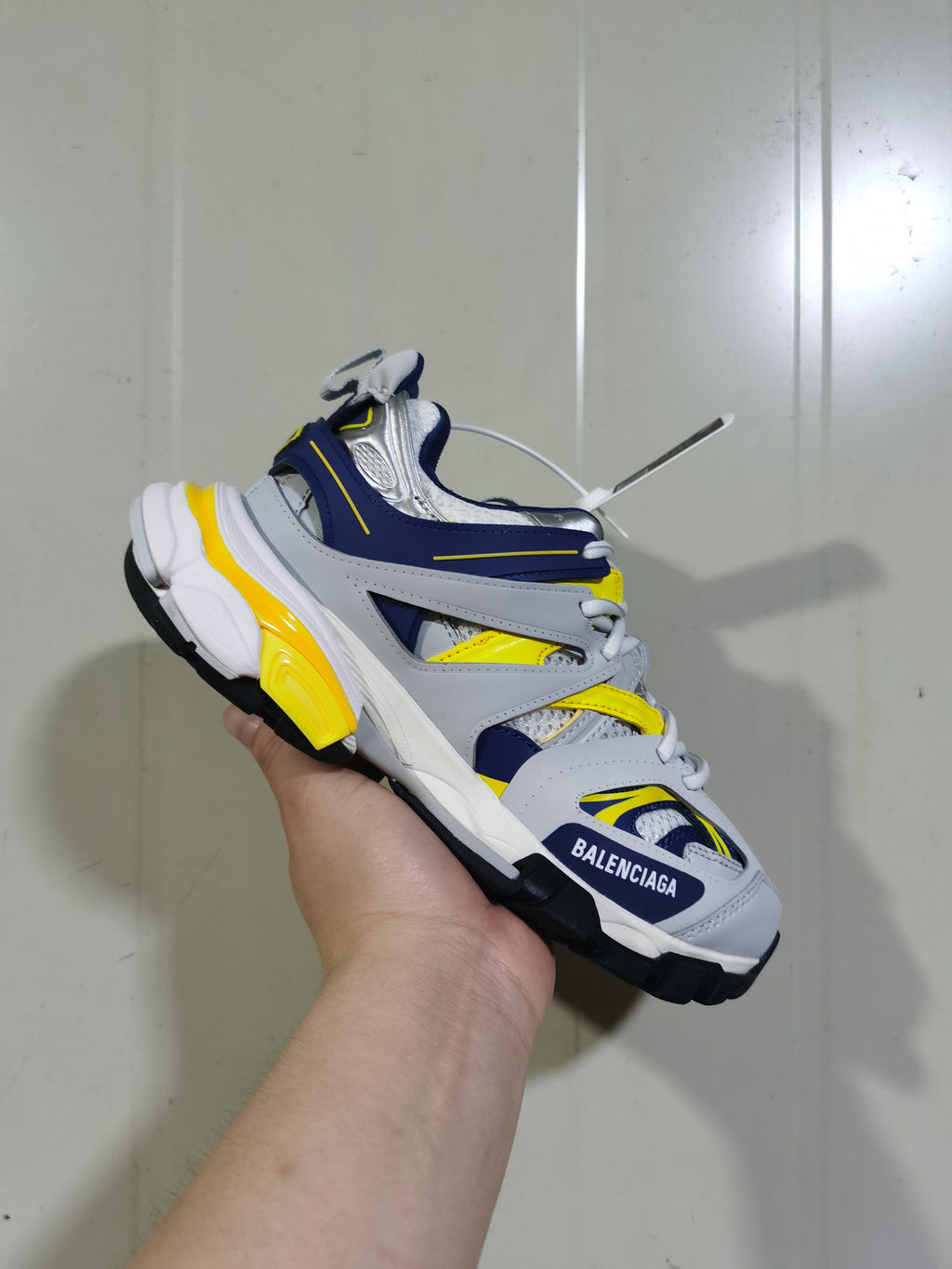 Close angled view of the Balenciaga Track sneaker showing the layered upper, mesh sections, yellow accents and black lugged outsole.