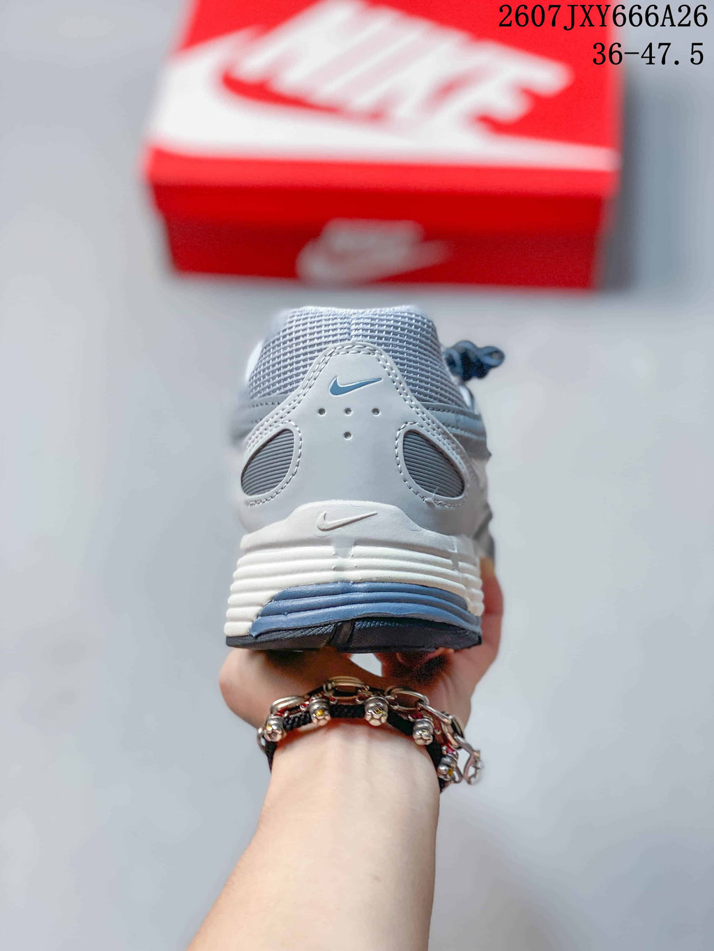 Rear view of a gray and white Nike P-6000 sneaker showing the padded collar, heel overlays, and layered midsole.