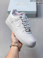 Angled side view of the white Nike low-top sneaker showing the Swoosh, perforated toe, and textured outsole.