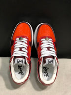 Top-down view showing the orange perforated toe boxes, white laces and branded insoles.