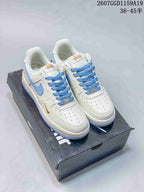 Pair of white Nike low-top sneakers with light blue accents and gold-toned branding displayed on a shoebox.