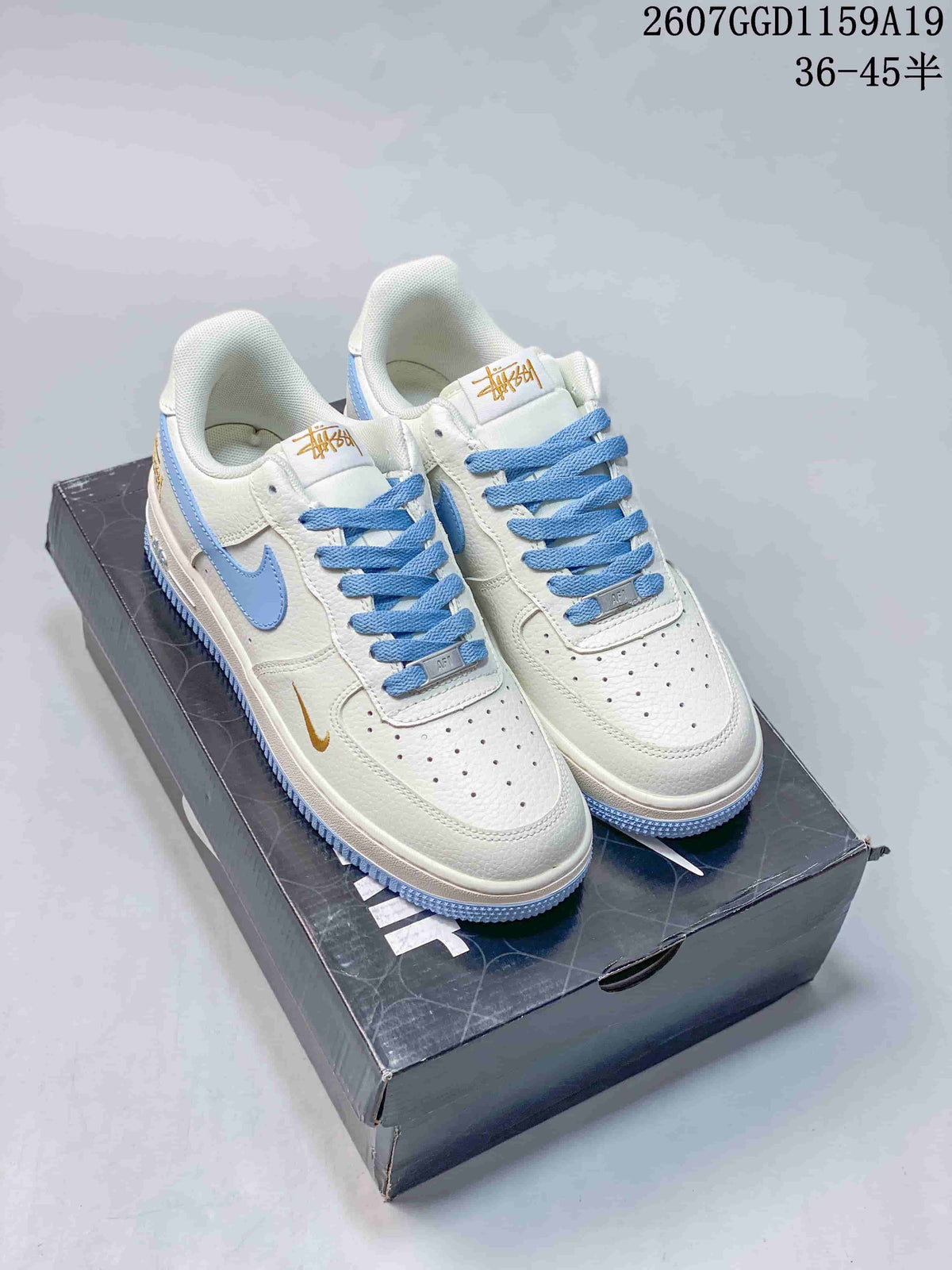 Pair of white Nike low-top sneakers with light blue accents and gold-toned branding displayed on a shoebox.