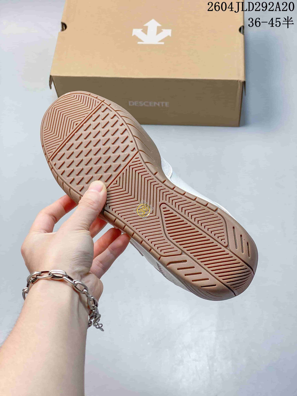 Close-up of the patterned gum-colored outsole with the DESCENTE shoe box in the background.