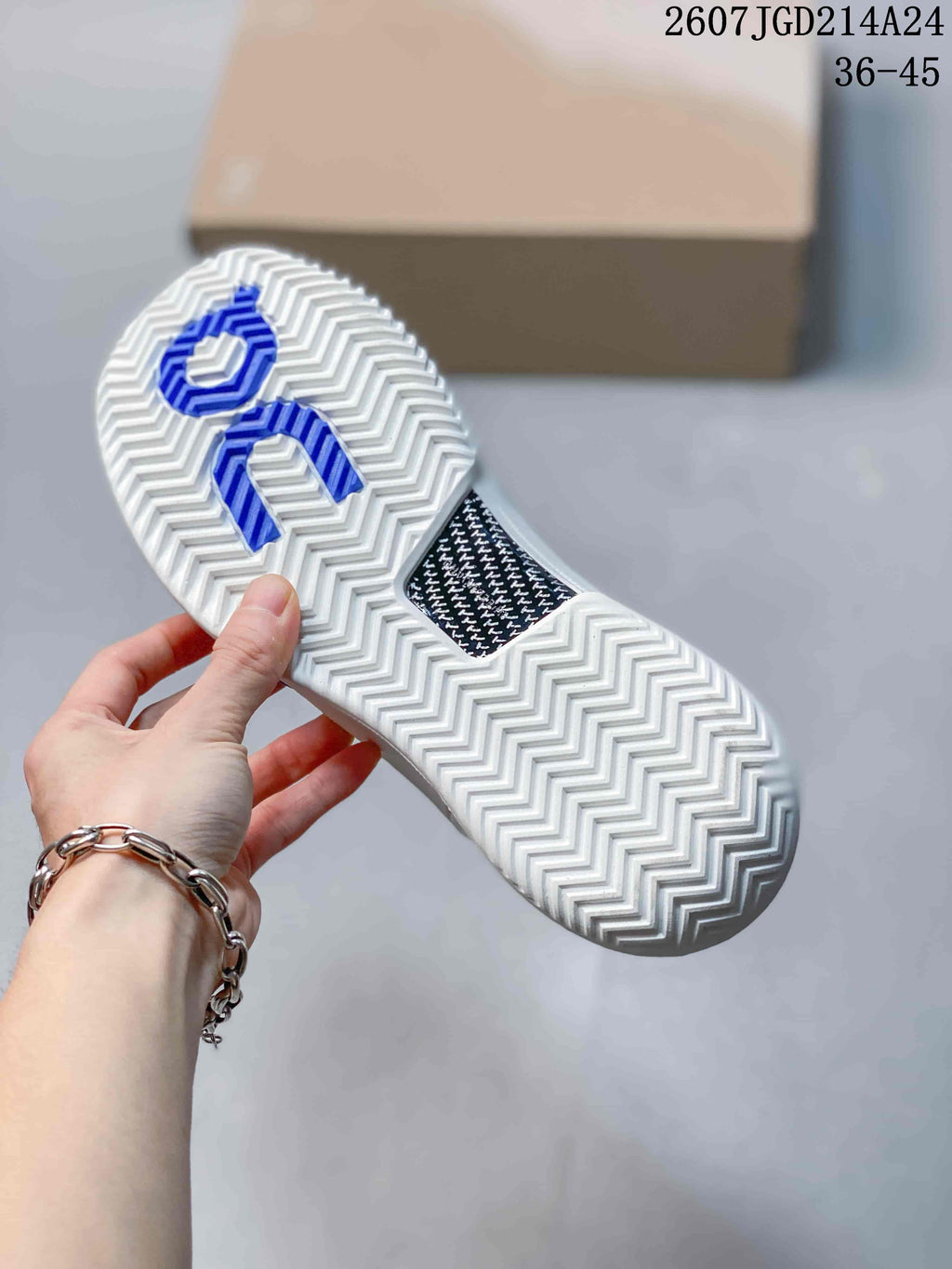 Bottom view of the white shoe showing the repeating zigzag outsole tread and blue On logo details.