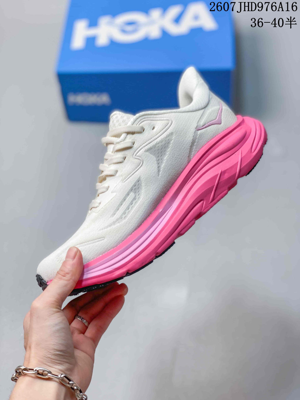 Side view of a white HOKA Clifton 10 sneaker with bright pink midsole, layered upper details, and dark outsole sections; image text shows size range 36–40.5.
