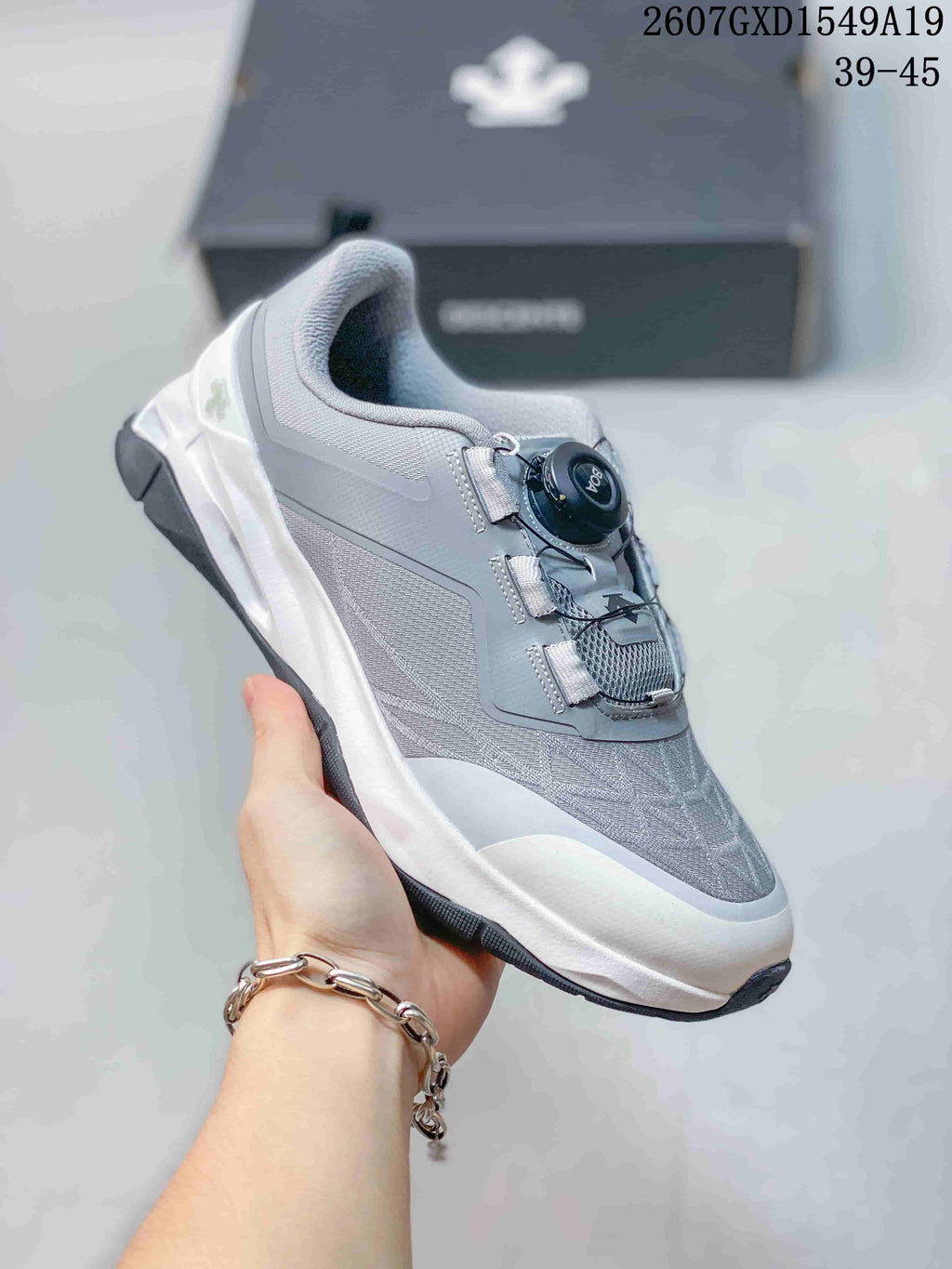 Side and top view of a light gray DESCENTE training shoe with a white midsole and dial-style closure.