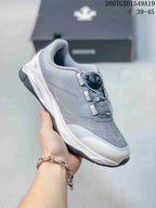 Side and top view of a light gray DESCENTE training shoe with a white midsole and dial-style closure.