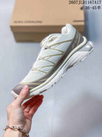 Side profile of the beige and brown Salomon XT-6 showing the textile-style upper, layered overlays, low-top shape, and textured outsole.