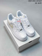 Pair of white low-top Nike sneakers with pale beige Swoosh accents displayed on a shoebox; text shows code 2607 JHD1197A27 and size range 36–46.