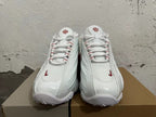 Front view of white lace-up sneakers with red details