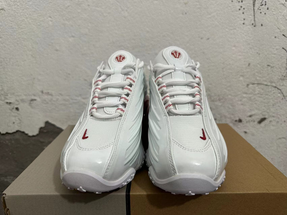 Front view of white lace-up sneakers with red details