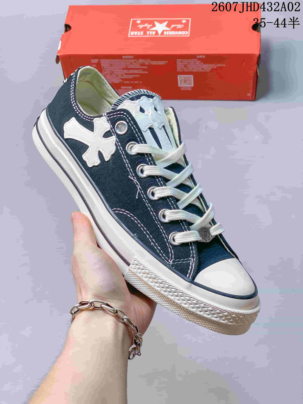 Angled view of the navy and white low-top sneaker with side cross-shaped detail and white rubber toe cap.