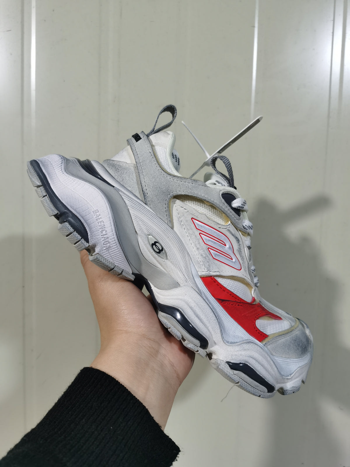 Angled view of white, grey and red Balenciaga Cargo sneakers showing layered panels, mesh sections and chunky treaded soles.