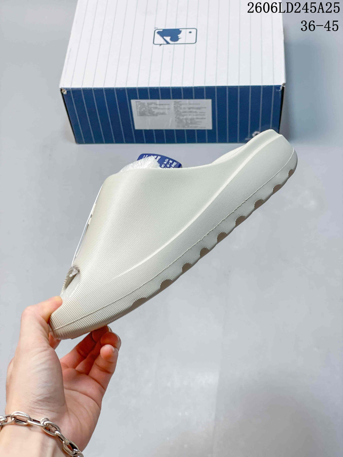Side profile of an off-white open-toe slide sandal with a raised sole.