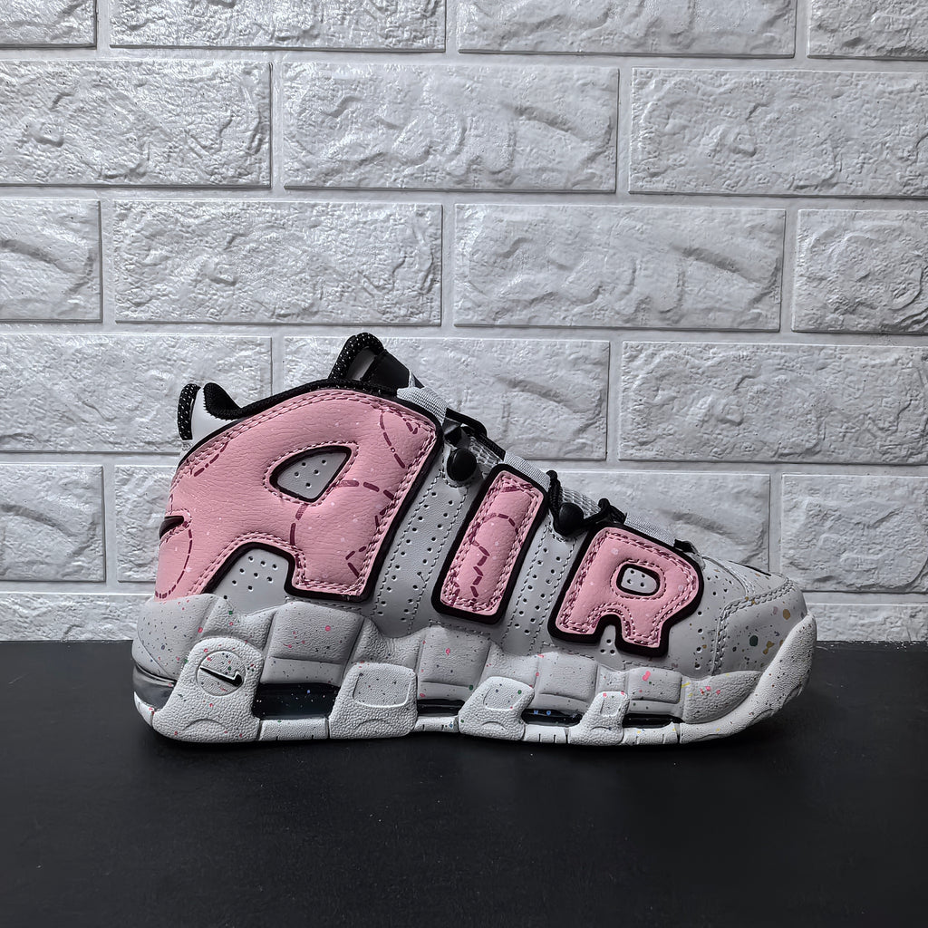 Side view of pink and grey Nike sneakers with oversized AIR lettering and speckled sole